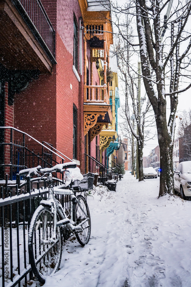 View of Roy street  and snow-covered bike in Plateau Mont-Royal neighborhood on a snowfall day in Montreal, Quebec (Canada)