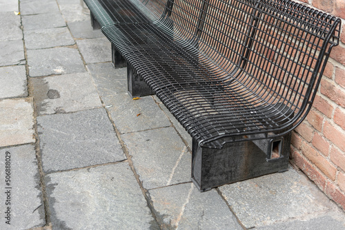 Wallpaper Mural Side view of a black bench made of metal rods on a paved gray stone sidewalk against an old red brick wall Torontodigital.ca