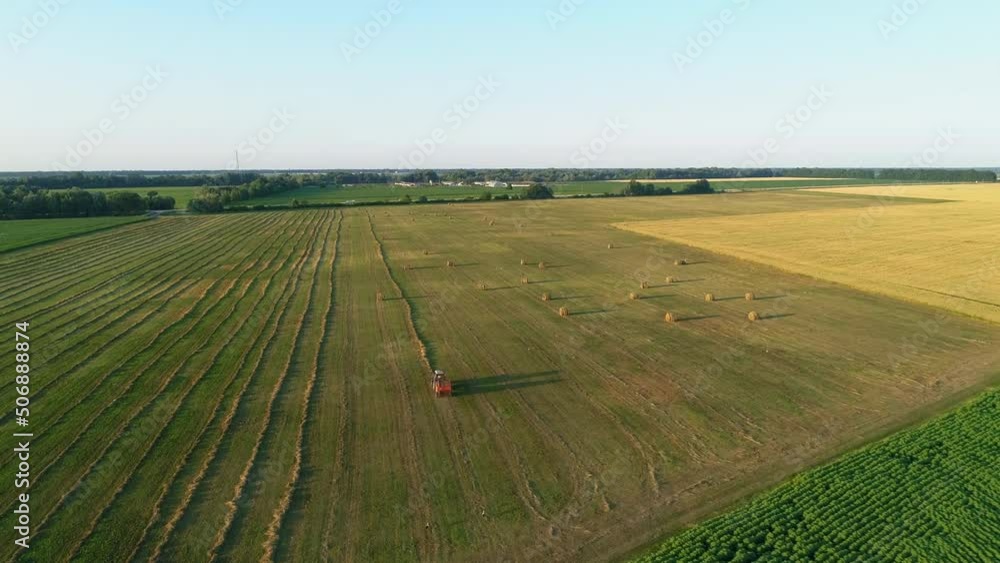 Aerial view tractor with baling machine making silage bales on farmland at agricultural field. Drone shot haystack and harvesting dry grass for agriculture. Farmers season to cut and harvest crops Aerial view tractor with baling machine making silage bales on farmland at agricultural field. Drone shot haystack and harvesting dry grass for agriculture. Farmers season to cut and harvest crops
