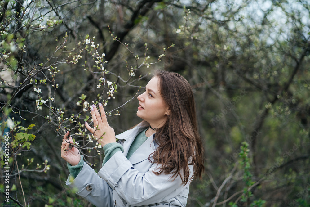 beautiful girl with long hair in a grey trench coat outdoors in cherry blossoms in spring beautiful girl with long hair in a grey trench coat outdoors in cherry blossoms in spring