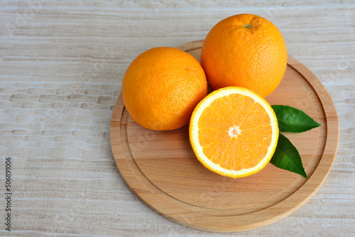 orange fruits on cutting board with green leaves, close-up