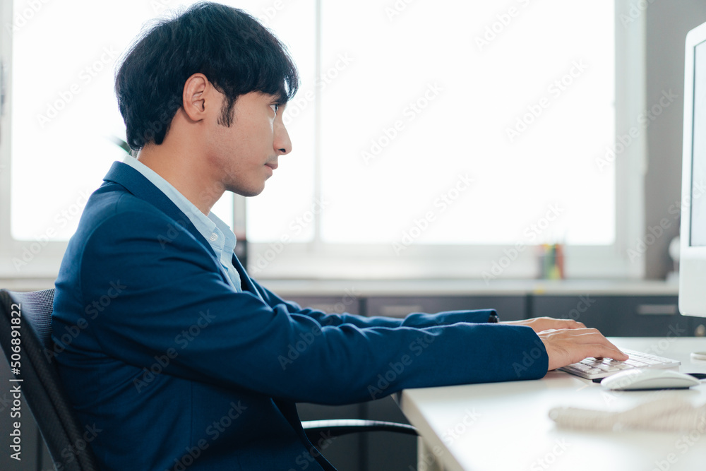 Asian male employee typing on computer keyboard working at desk in the office. corporate business or financial advisor career . copy space Asian male employee typing on computer keyboard working at desk in the office. corporate business or financial advisor career . copy space