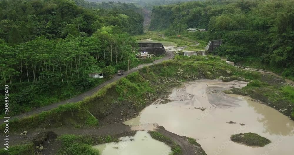 Drone shot of truck crossing road beside lake former sand mine in wilderness of Indonesia Drone shot of truck crossing road beside lake former sand mine in wilderness of Indonesia