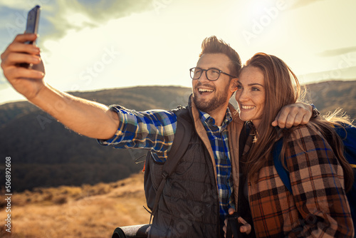 Couple with backpacks making selfie while they hiking on the mountain.