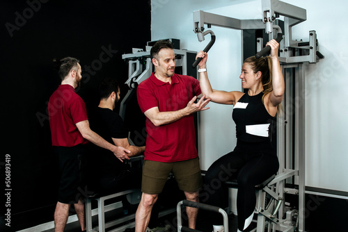 blonde girl working out with her personal trainer on a gym machine