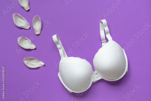 White new bra on a violet background. Bra, lace lingerie on a very peri purple background. Beauty blog concept. Top view, flat lay 