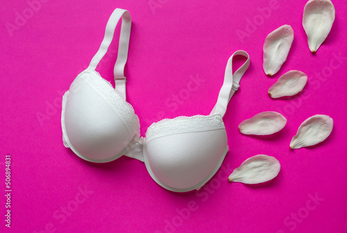 White new bra on a pink background. Bra, lace lingerie on a magenta background. Beauty blog concept. Top view, flat lay 