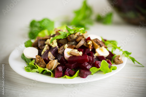 Salad with boiled beets, fried eggplants, herbs and arugula in a plate
