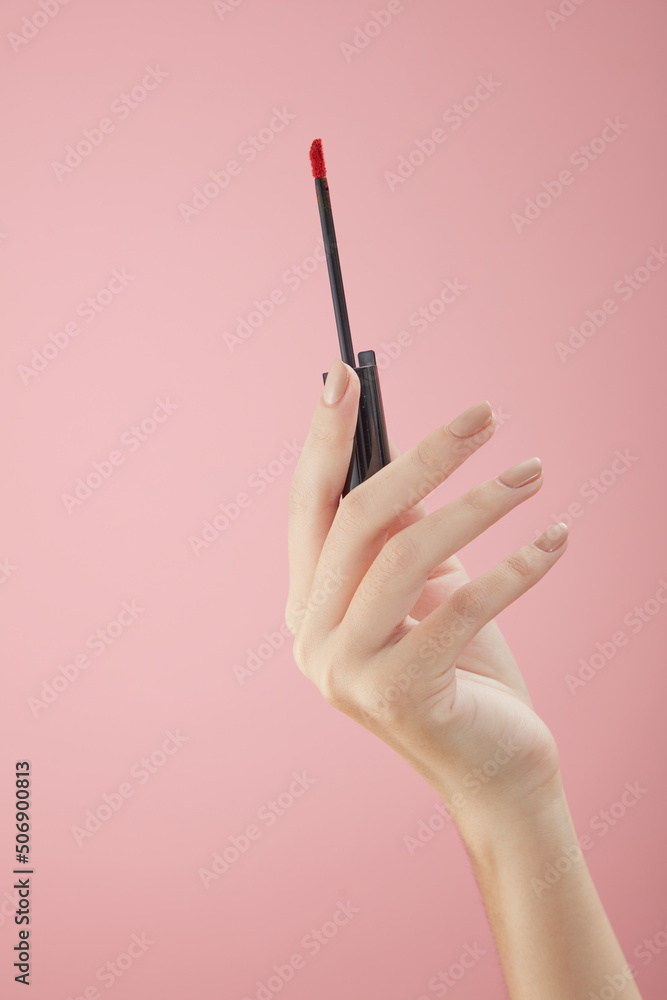 Top view of hand model using lipstick on hand in pink background for cosmetic advertising Top view of hand model using lipstick on hand in pink background for cosmetic advertising