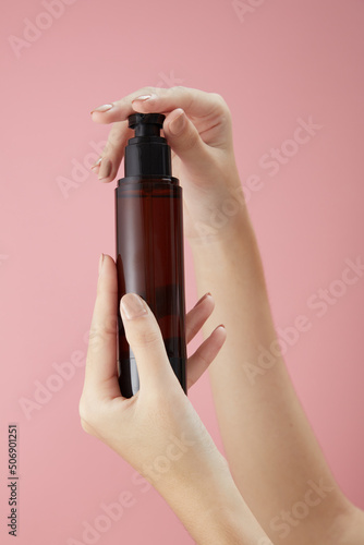 Front view of hand model holding cosmetic jar in pink background for cosmetic advertising 