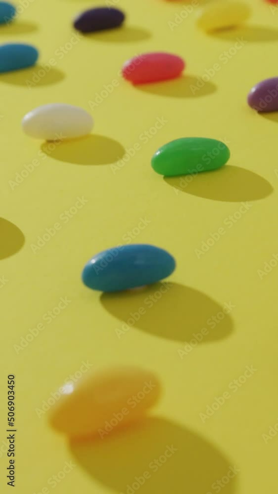 Video of overhead view of rows of multi coloured sweets over yellow background Video of overhead view of rows of multi coloured sweets over yellow background
