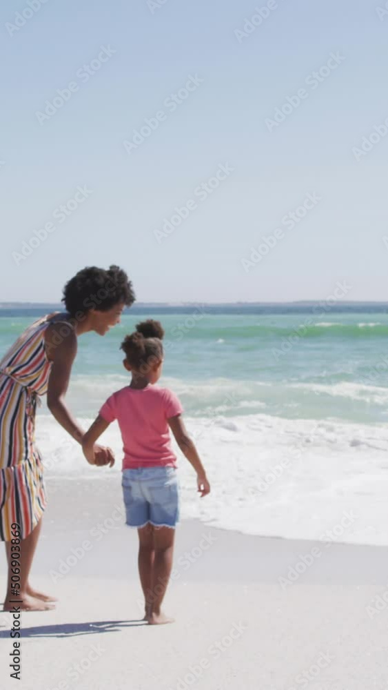 Smiling african american mother with daughter walking on sunny beach Smiling african american mother with daughter walking on sunny beach