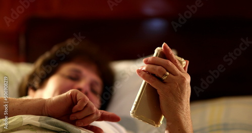 Married couple in bed using smartphone