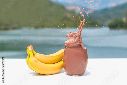 Tempting glass of splashing chocolate shake with bananas
