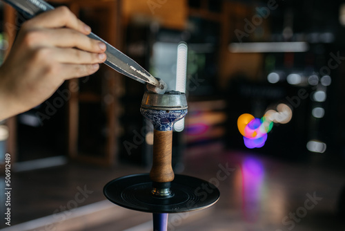 Hookah smoking at a party concept. Hookah stands on a wooden table in the interior of the restaurant. Smoking concept. Traditional hookah, spark, hookah sparks. Hookah on the table.