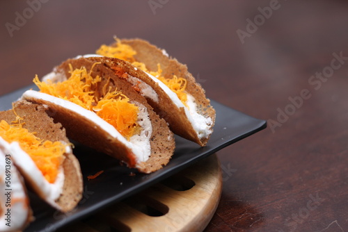 Thai Food, Thai Crispy Pancakes served in a black plate on a brown wooden table.