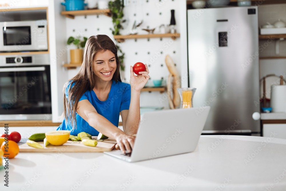 Young woman searching online recipes in the kitchen Young woman searching online recipes in the kitchen