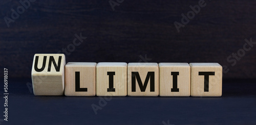 Limit or unlimit symbol. Turned wooden cubes and change the concept word Limit to Unlimit. Beautiful black table black background. Business limit or unlimit concept. Copy space.