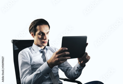 Young handsome businessman sitting on chair with digital tablet isolated on white background