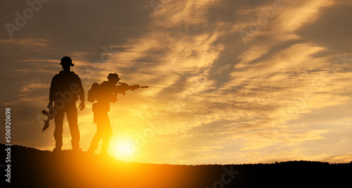 Silhouettes of soldiers standing against the backdrop of a sunset. Greeting card for Veterans Day, Memorial Day, Independence Day. USA celebration. Concept - patriotism, protection, remember honor. © hamara