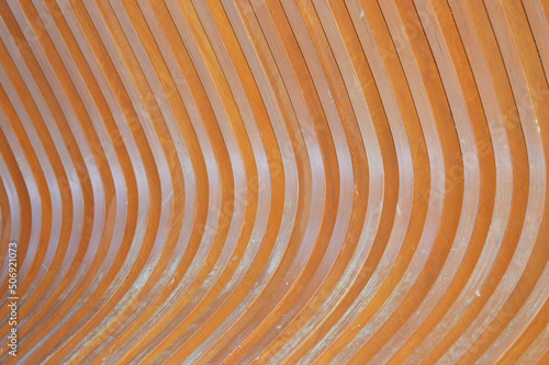 Wooden bench element, brown slats with a rounded edge. Abstract background.