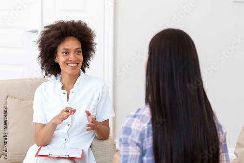 Woman at therapy session. Attentive psychologist. Attentive psychologist holding pencil in her hands making written notes while listening to her client photo