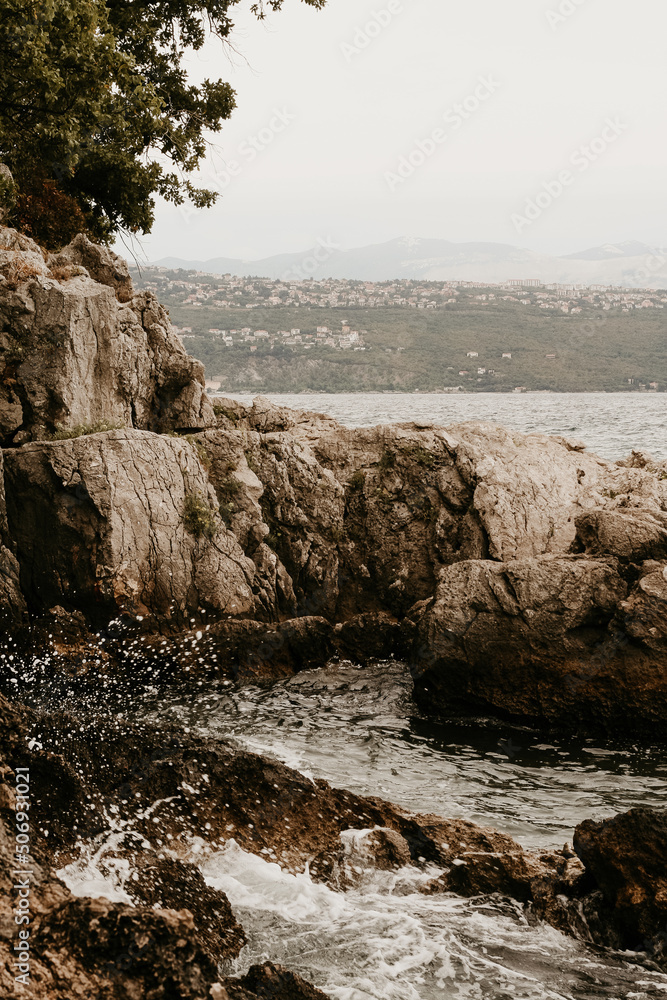 A big brown cliff in the sea in Opatija, Croatia. A city is in the hazy background, the water has tiny waves. Mediterranian seascape for relaxation. Copy space image. Beautiful coastline in Europe.
A big brown cliff in the sea in Opatija, Croatia. A city is in the hazy background, the water has tiny waves. Mediterranian seascape for relaxation. Copy space image. Beautiful coastline in Europe.