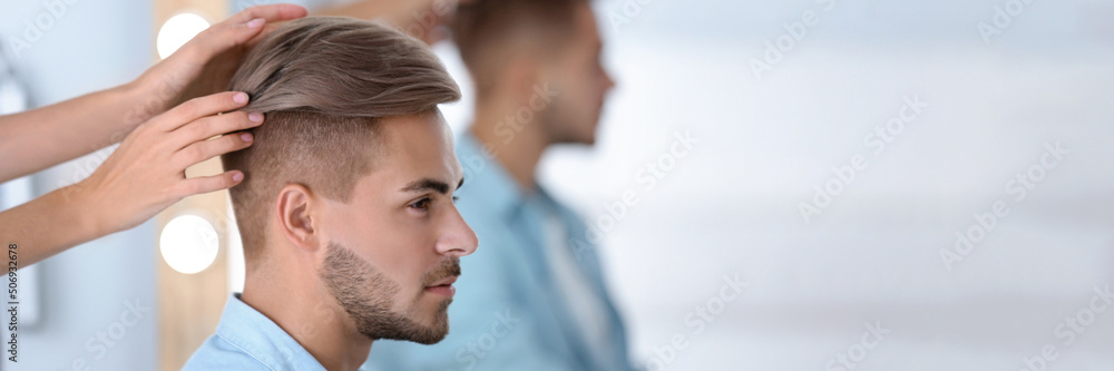 Obraz premium Professional hairdresser working with young man in barbershop. Banner design