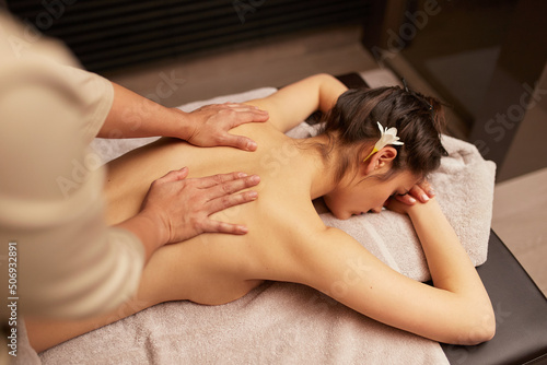 Top view of a hands of the masseur on the female caucasian back. Body healthy procedure.