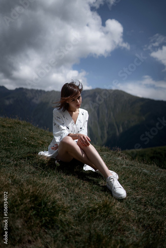 Slim attractive woman in a white dress relaxes on the grass.