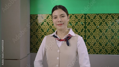 Portrait of Asian woman airport ground attendant in uniform and standing smile with salute respect Sawasdee Thai style at counter check in. Young female ground staff wait service for airline business. photo