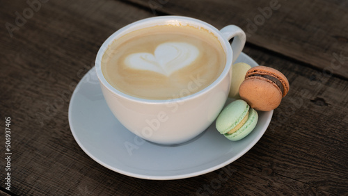 Cup of cappuccino served with colorful small macaroons
