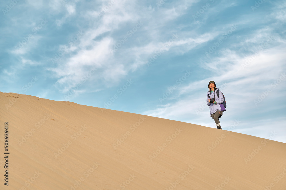 asian female photographer walking on ridge of sand dune asian female photographer walking on ridge of sand dune