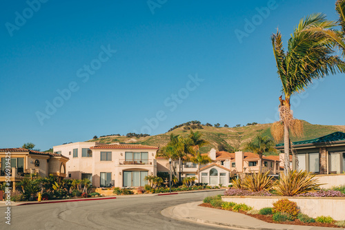 Beautiful houses with nicely landscaped front the yard and clear blue sky on background in a small beach town, California