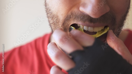 Young male putting mouthguard before boxing sparring training photo