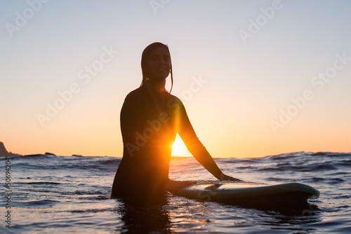 Surfer girl waiting for a wave in the water at sunset © Iván Berrocal