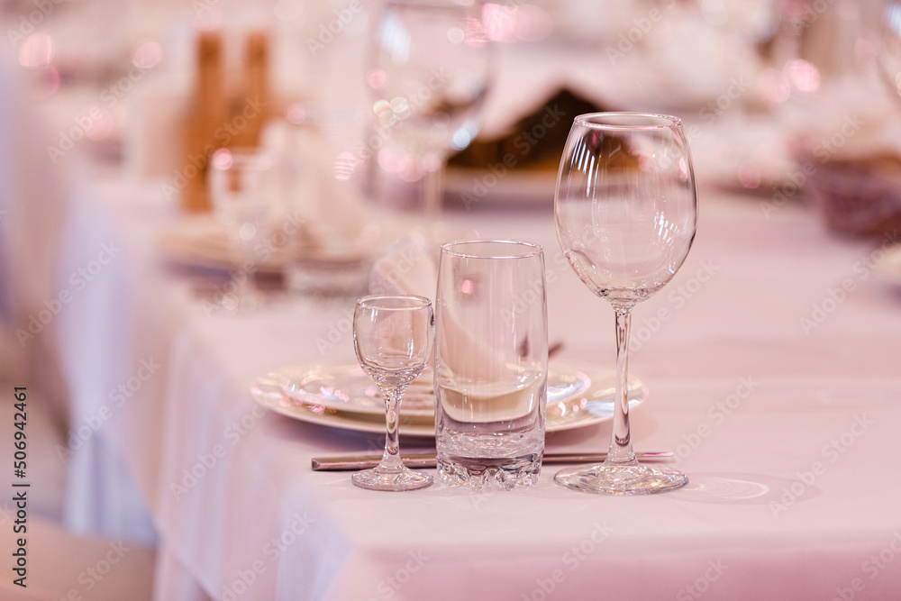 Empty glass set in restaurant. wedding, decor, celebration, holiday concept - romantic table setting with white tablecloth, plates, crystal glasses