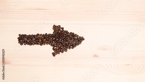 Wooden craft surface as a comfortable background wall or floor with different structures of light wood full of many aroma coffee beans. Cupid straw shaped coffee beans. For coffee lovers.