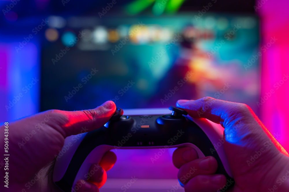 Close-up. Modern gamepad. A gamer plays video games on a technological background on a TV screen. Virtual reality, entertainment, communications, cyberspace.