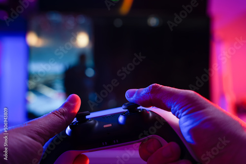 Joystick in the hands of a gamer. Technological background. Close-up. Video games, entertainment, online competition with friends, recreation, game strategy, new emotions.
