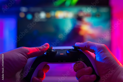 Close-up. Modern gamepad. A gamer plays video games on a technological background on a TV screen. Virtual reality, entertainment, communications, cyberspace. photo