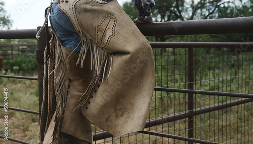 Ranch hand shows chaps on working cowboy for western wear lifestyle. photo