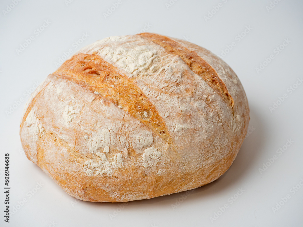 A close-up of a whole fresh crispy delicious round-shaped wheat bread on a white background. Insulated items, baking, side vew