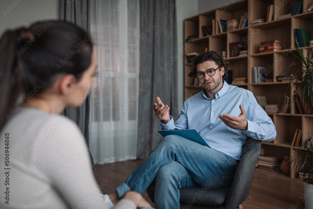 Serious young caucasian guy doctor psychologist advises woman in modern clinic interior, free space Serious young caucasian guy doctor psychologist advises woman in modern clinic interior, free space