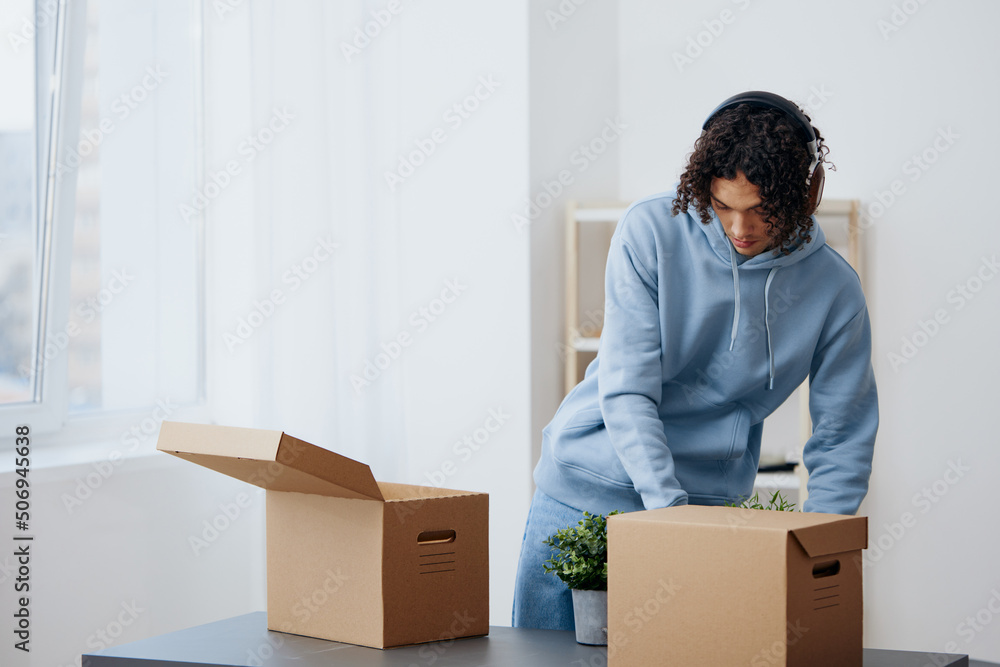 handsome guy in headphones unpacking with box in hand interior handsome guy in headphones unpacking with box in hand interior