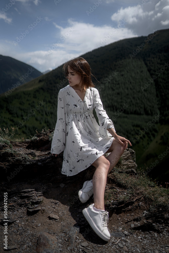 Naklejka premium Elegant young woman in a white dress is posing and looking away.