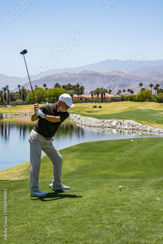 Male golfer on profession golf course hitting over water