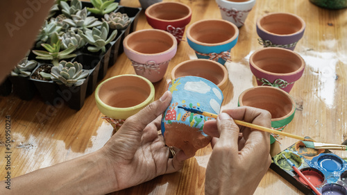 Hands of a Latin woman, painting clay pots to plant succulent plants