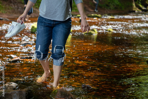 Woman Walking Barefoot In Mountain River. Finnich Glen.The Devil’s Pulpit in Scotland. UK. 