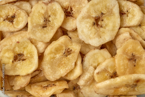 Banana chips background top view. Dried banana slices texture. Heap of dried bananas.